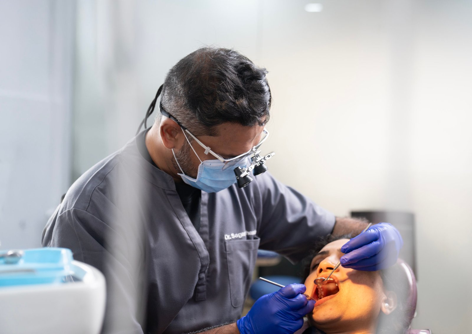 Dr. Sagar Lokhande, in a white coat, explaining dental care using a model in a professional clinic setting.